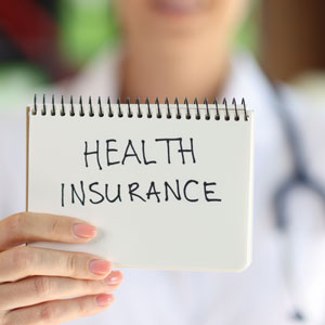 A medical professional holds a notebook titled HEALTH INSURANCE claim personal injury