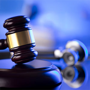 A wooden gavel is in focus, with a stethoscope blurred in the background, symbolizing medical litigation.