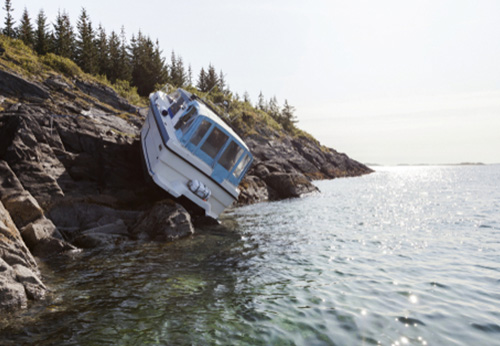 Small boat crashed on rocky shore, representing maritime property damage law.