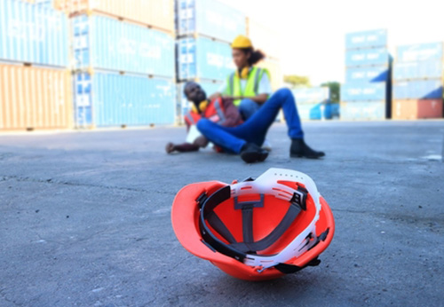 Injured worker at a shipping port near a hard hat, illustrating dockworker injury law.